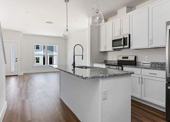 A kitchen with white cabinets and a granite countertop.