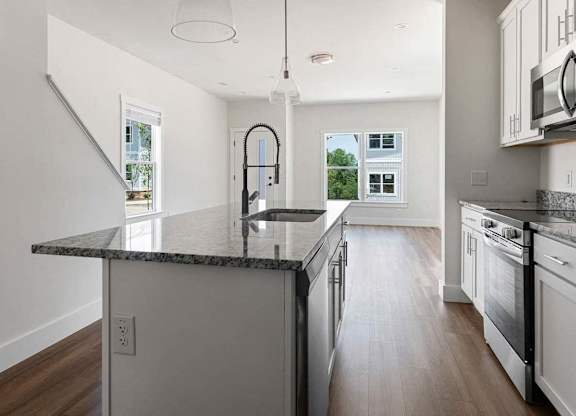 A modern kitchen with a granite countertop and stainless steel appliances.