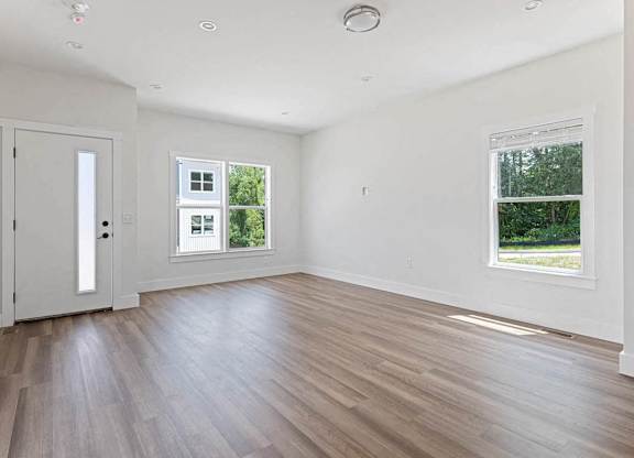 A room with a white door and a window with a view of trees.