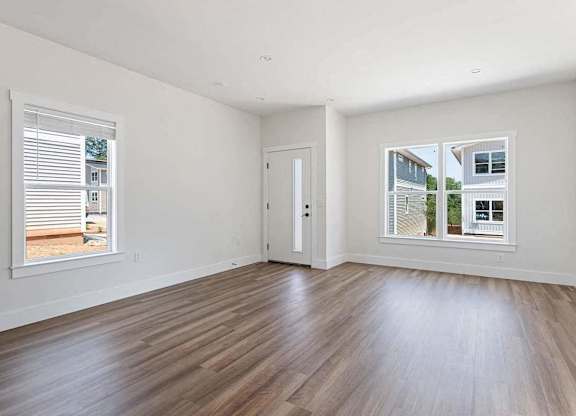 A room with wooden floors and two windows showing an outdoor view.