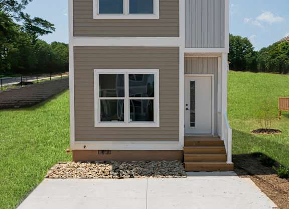 A small house with a grey and white exterior and a brown door.