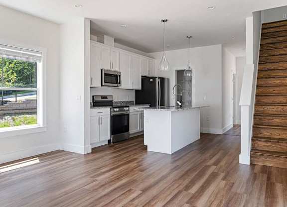 A modern kitchen with wooden floors and white cabinets.