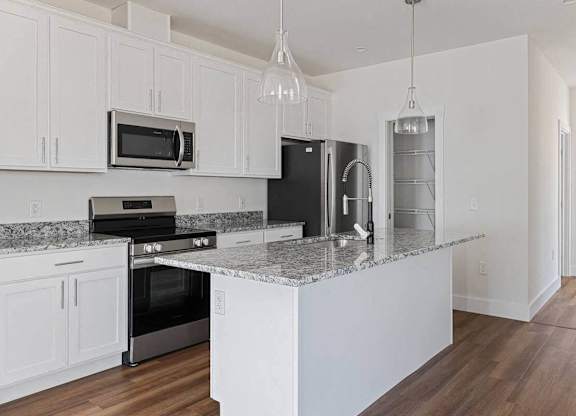 A kitchen with white cabinets and a granite countertop.