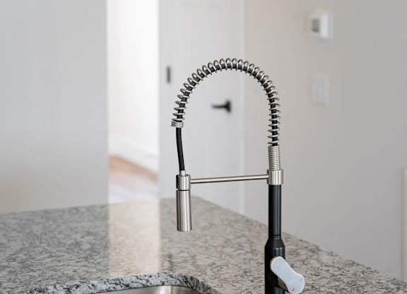 A kitchen sink with a granite countertop and a pull-down faucet.