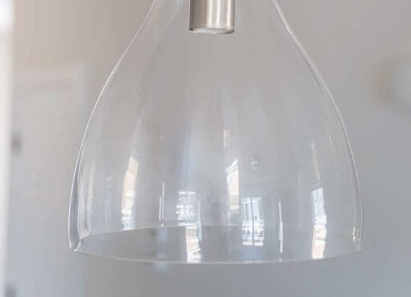 A clear glass pendant light hanging from a metal rod.