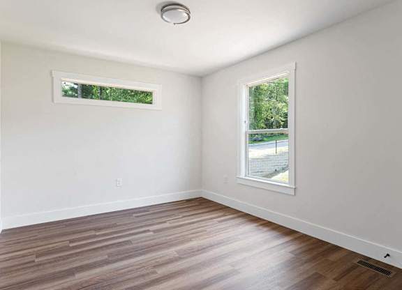 A room with a window and a wooden floor.
