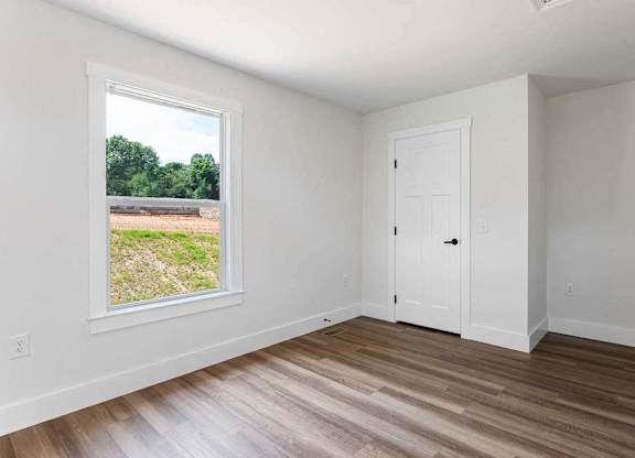 A room with a white door and a window showing an outdoor view.