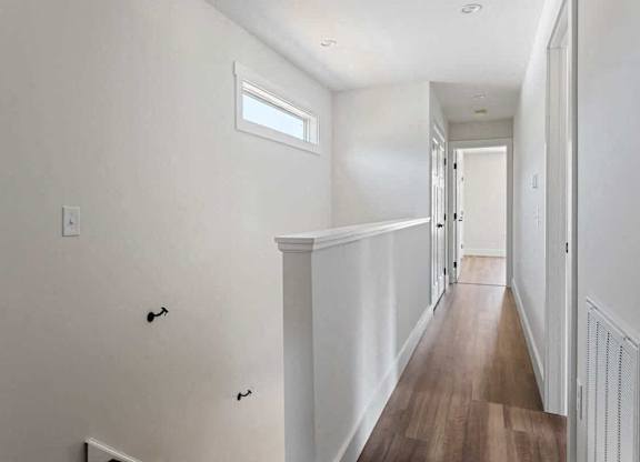 A long hallway with white walls and wood flooring.