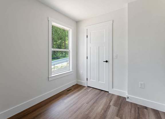 A room with a white door and a window showing greenery outside.
