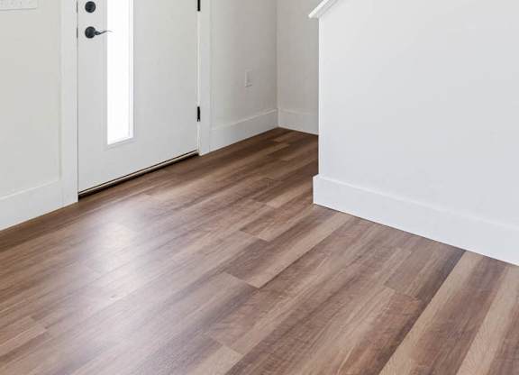 A white door is in a room with wood flooring.