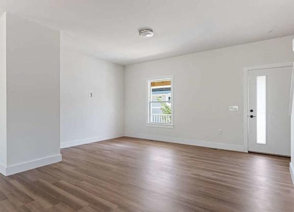 A room with wooden flooring and white walls.