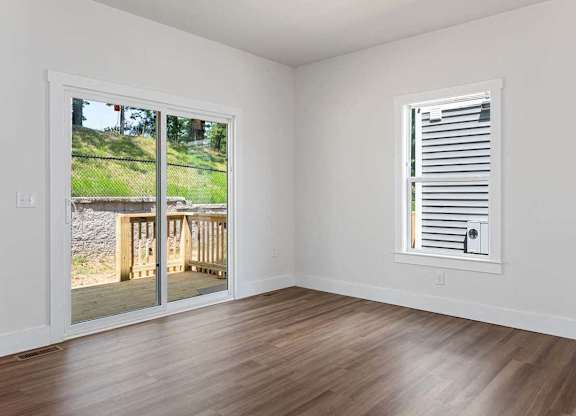 A room with a sliding glass door and a window with blinds.