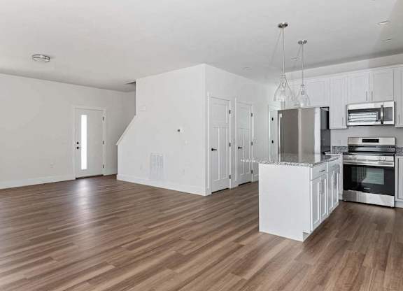 A kitchen with white cabinets and a wooden floor.