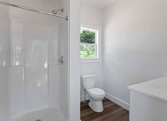A white bathroom with a toilet, tub, and shower.