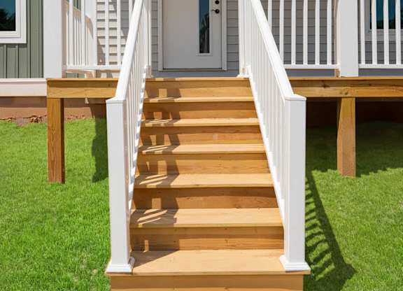 A house with a white front porch and stairs leading to the door.