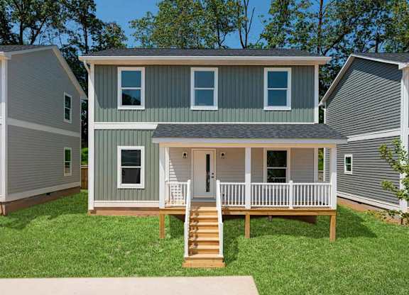 A house with a grey and white exterior and a wooden deck.