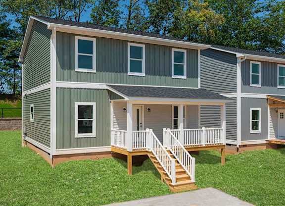 A two-story house with a grey and green exterior and a white porch.