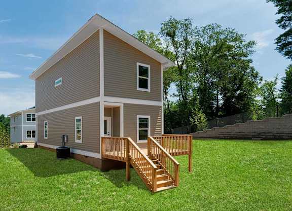 A small house with a wooden deck in the front yard.