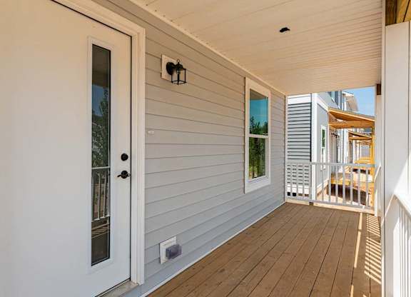 A white door is open to a balcony with a table and chairs.