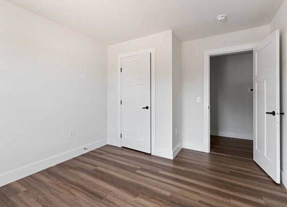 A room with a white door and a brown floor.