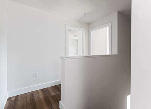 A white room with a window and wooden floors.