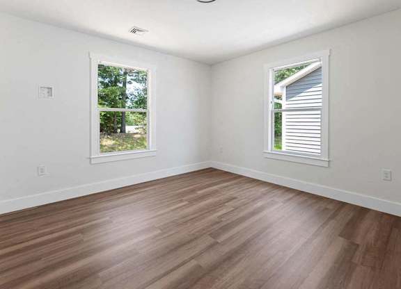 A room with wooden floors and two windows.