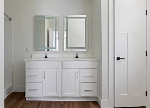 A white bathroom vanity with two mirrors above it.