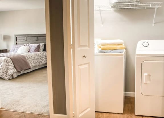 a bedroom with a washer and dryer and a closet with a bed