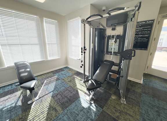 A gym room with a weight machine and a chair.