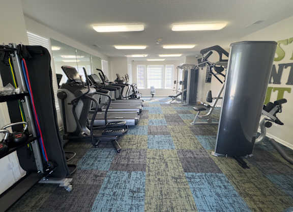 A gym with treadmills, elliptical machines, and other exercise equipment.