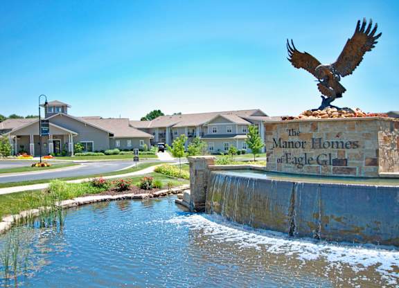 A statue of an eagle is perched on a sign that says "The Manor Homes of Eagle Glen.".