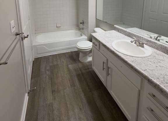 A bathroom with a white tub, toilet, and sink.