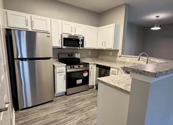 A kitchen with a refrigerator, oven, and microwave.