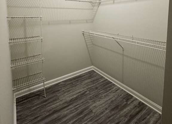 Empty walk in closet with shelves and wood floors.