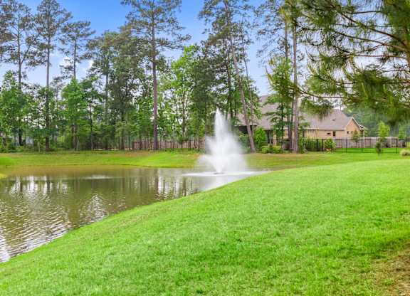a fountain in a pond with a house in the background
