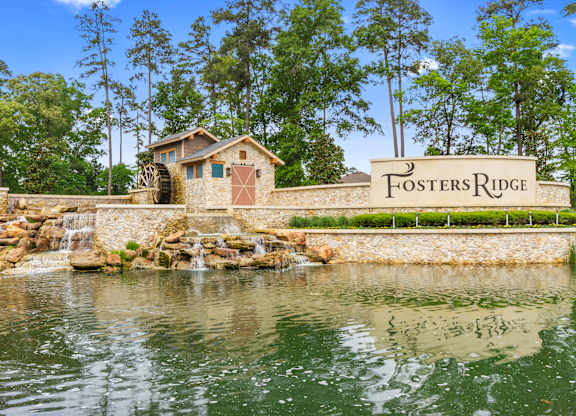 a stone retaining wall with a sign that reads fosters ridge and a water feature with a