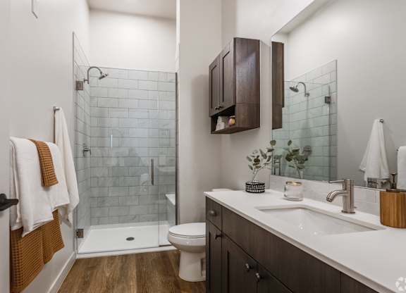 A bathroom with a white toilet, a white sink, and a glass shower.