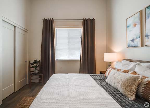 A bedroom with a large bed and a window with curtains.
