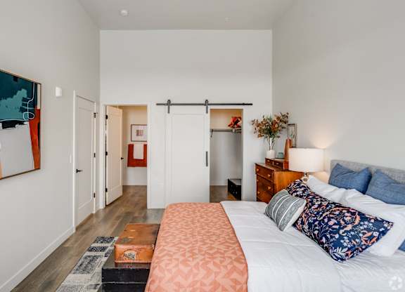 A bedroom with a bed, nightstand, and a painting on the wall.