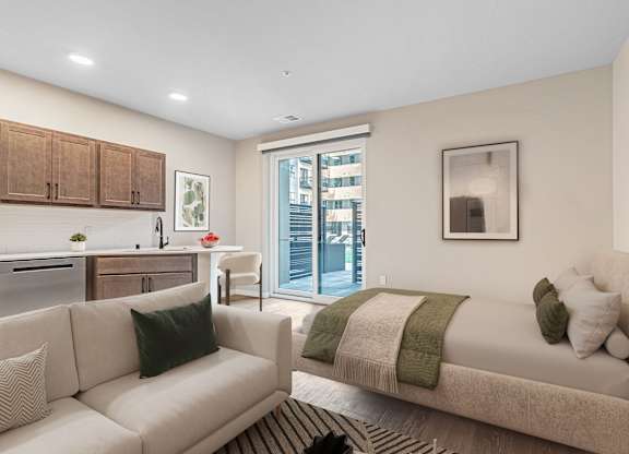 A modern living room with a couch, a bed, and a kitchen area.