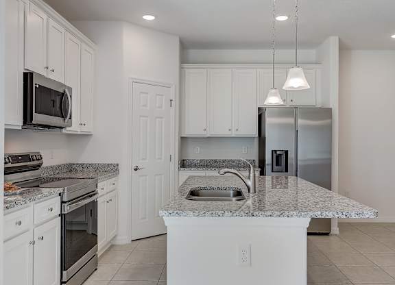 A kitchen with white cabinets and a marble countertop.