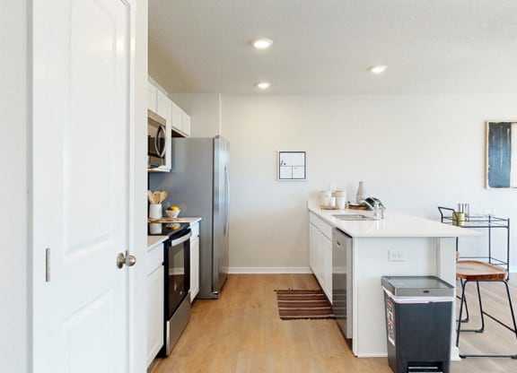 an open kitchen and dining room with a stainless steel refrigerator and stove and a counter