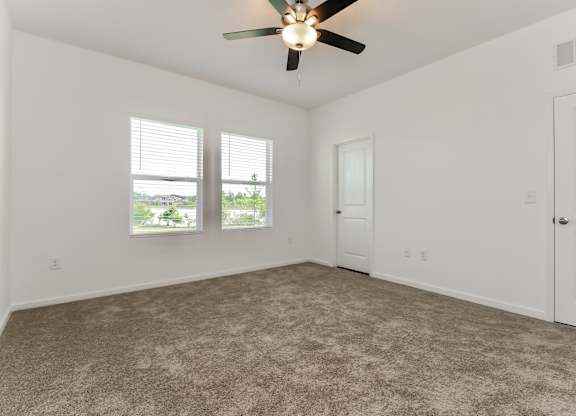 A room with a ceiling fan and carpeted floor.