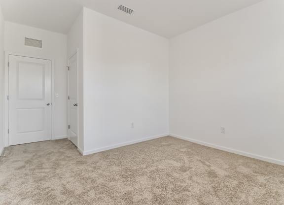 A room with a carpeted floor and two doors.