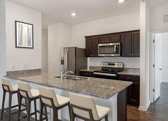 A kitchen with a granite countertop and bar stools.