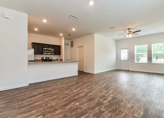 A spacious living room with a kitchen area in the background.