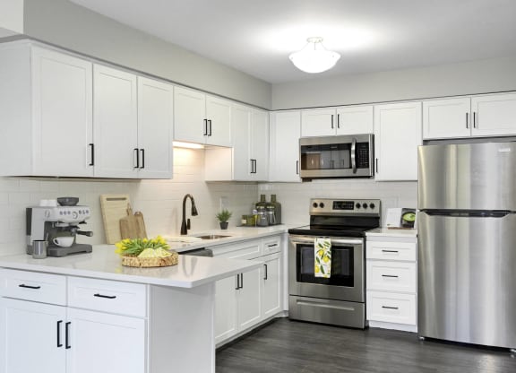 Laurel West End Apartments in Golden Valley, MN photo of kitchen with white cabinets, stainless-steel appliances and hardwood flooring