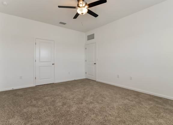 A room with a ceiling fan and carpeted floor.