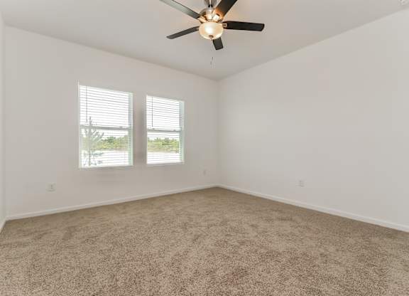 A room with a ceiling fan and carpeted floor.