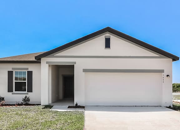 A white house with a black roof and a garage door.
